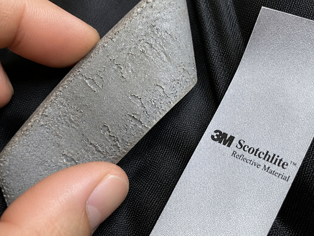 Close-up comparison of new versus worn-out reflective motorcycle gear material.